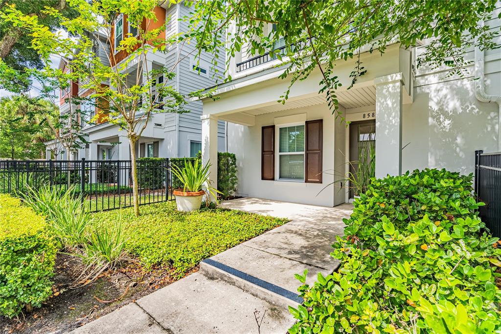 A concrete walkway leads to the covered front porch of a multi-story residential building — 858 N THORNTON AVENUE, ORLANDO, FL