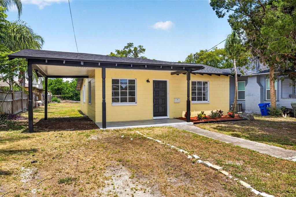 A yellow, single-story house with a black-trimmed carport and a front walkway — 834 E LIME STREET, LAKELAND, FL
