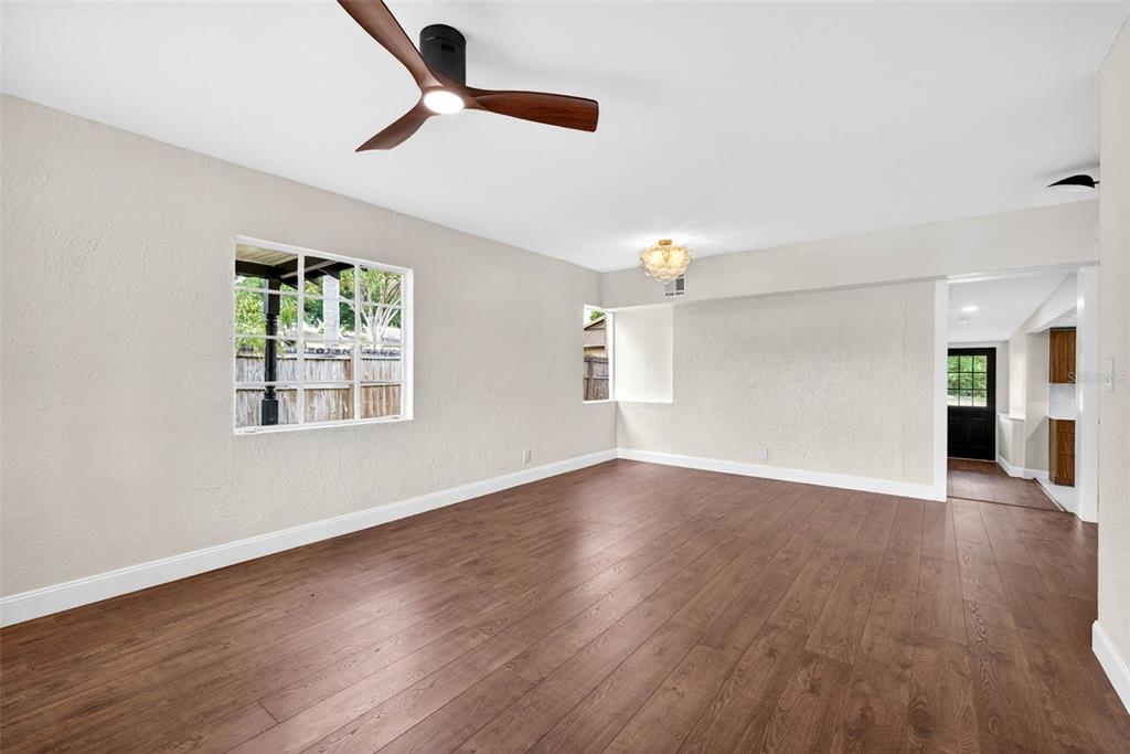 An empty living room features wood-look flooring, a ceiling fan, and a large window — 834 E LIME STREET, LAKELAND, FL