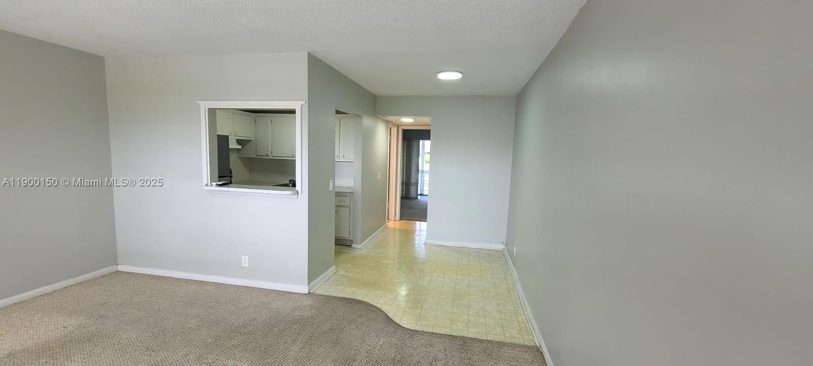 An interior view shows a carpeted living area adjacent to a tiled kitchen pass-through — 92 Berkshire D # 92, West Palm Beach FL 33417, WEST PALM BEACH, FL