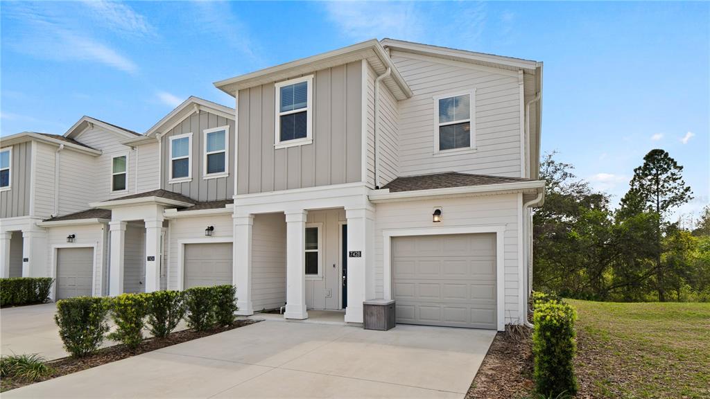 A row of light-colored two-story townhouses with attached garages and small front lawns — 7428 STONE CREEK TRAIL, KISSIMMEE, FL