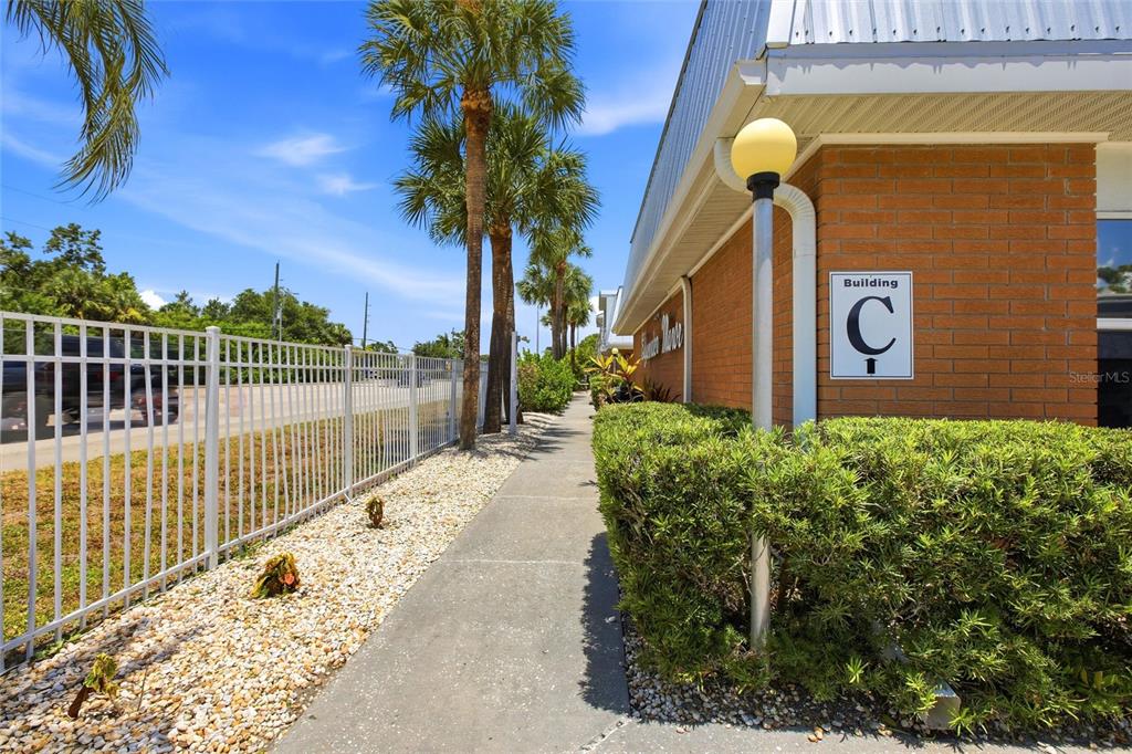 A sidewalk runs alongside a brick building labeled Building C with palm trees nearby — 22333 EDGEWATER DRIVE UNIT C2, PUNTA GORDA, FL