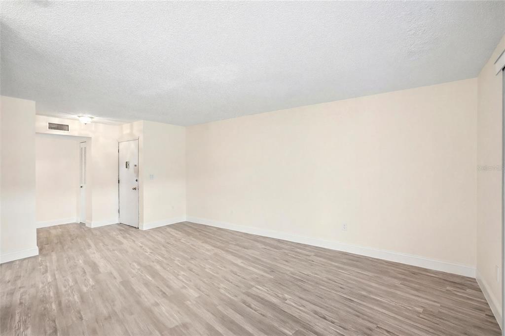 An empty room with light-colored walls, a white door, and wood-look laminate flooring — 22333 EDGEWATER DRIVE UNIT C2, PUNTA GORDA, FL