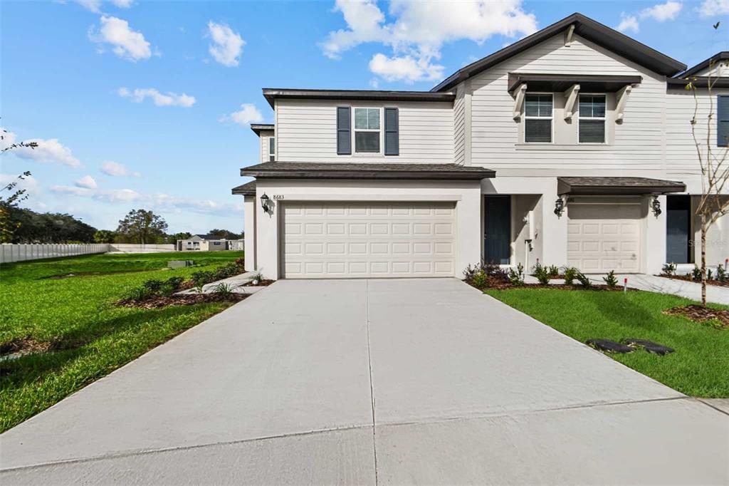 A two-story suburban townhouse with light siding, a two-car garage, and a concrete driveway — 8683 HOLLY GROVE COURT UNIT Calistoga, RIVERVIEW, FL