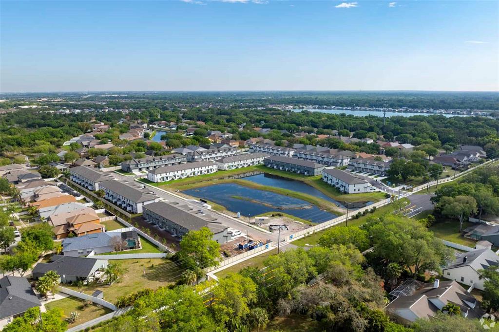 An aerial view shows a residential neighborhood with townhomes surrounding a central retention pond — 8683 HOLLY GROVE COURT UNIT Calistoga, RIVERVIEW, FL