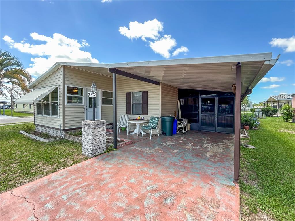 A single-story mobile home features light siding, a large carport, and a concrete driveway — 36412 LE SABRE WAY, ZEPHYRHILLS, FL