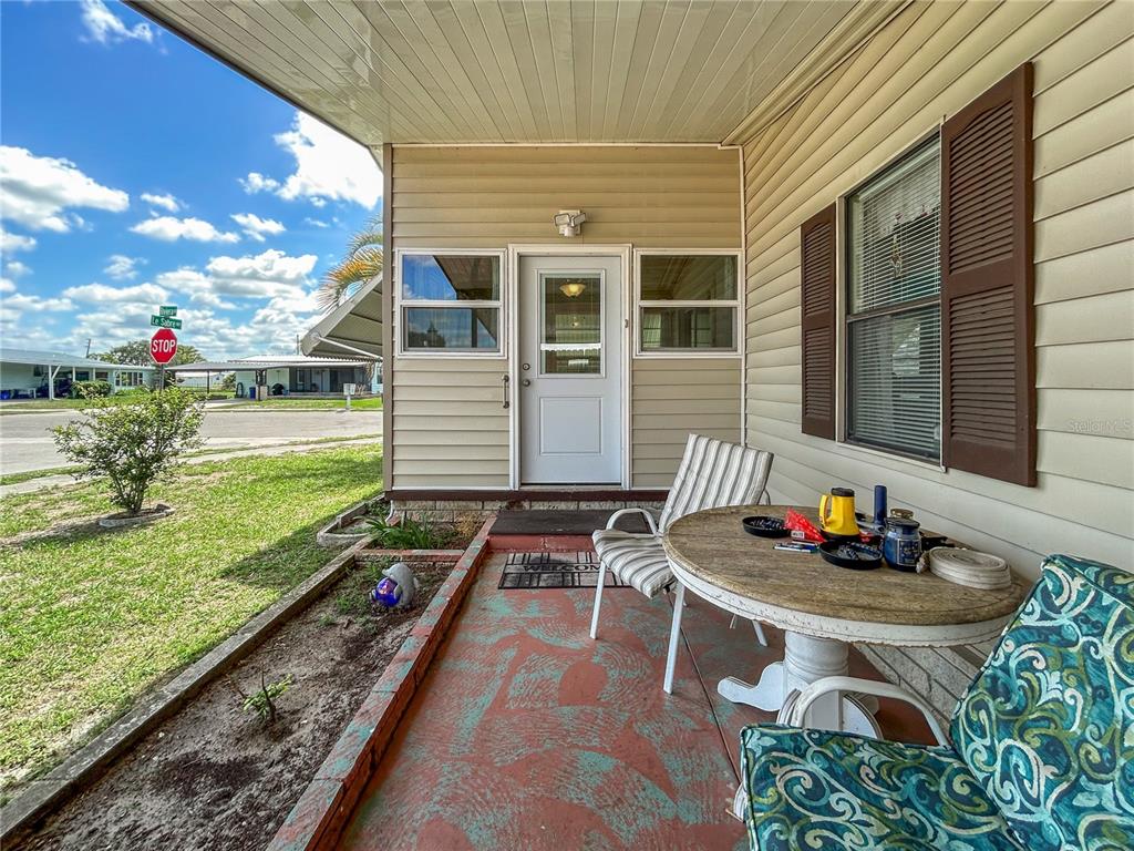 A covered porch with a table, chairs, and a view of a street intersection — 36412 LE SABRE WAY, ZEPHYRHILLS, FL