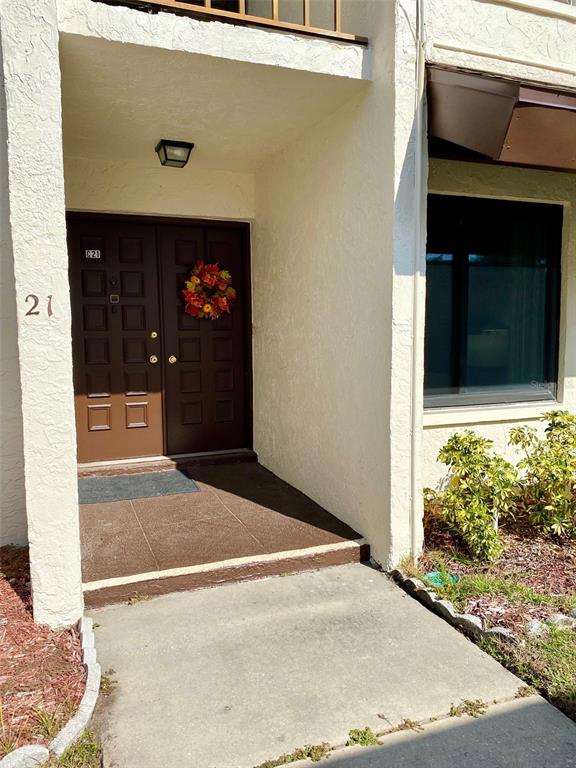 A brown double front door with a wreath sits under a covered entryway — 2209 BELLEAIR ROAD UNIT C21, CLEARWATER, FL