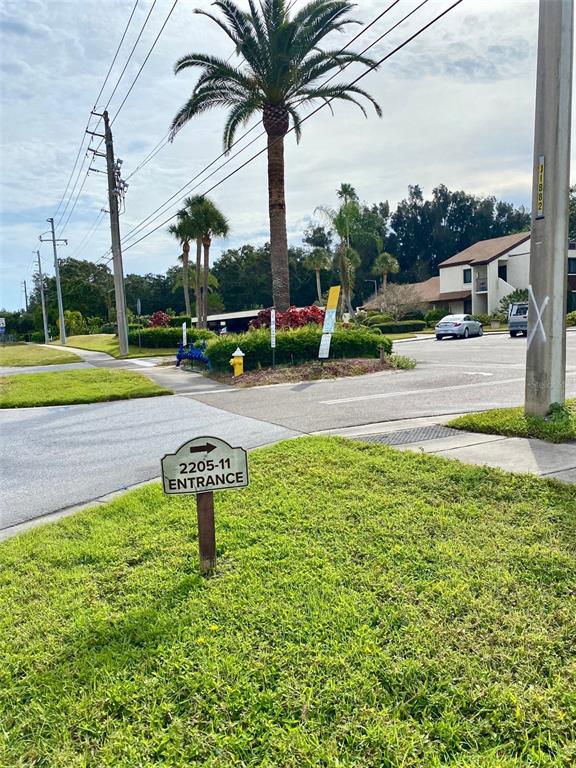 A sign points toward an entrance near a palm tree and a residential building — 2209 BELLEAIR ROAD UNIT C21, CLEARWATER, FL