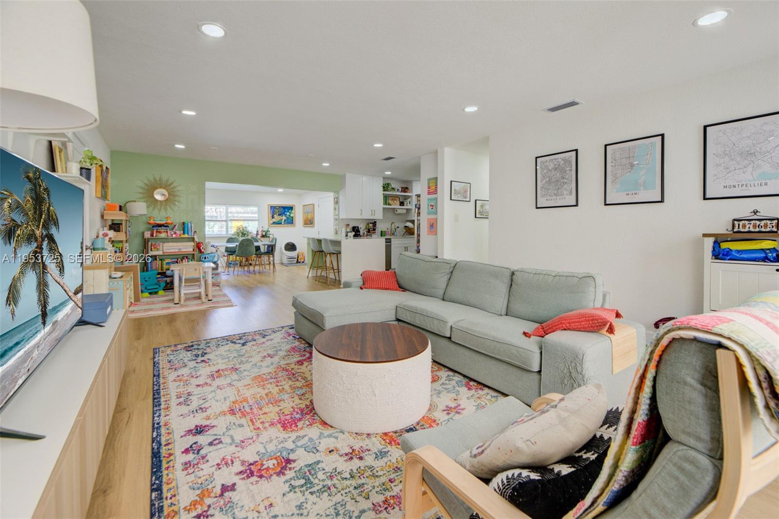 A living room features a sectional sofa, a patterned rug, and an open-concept kitchen area — 1765 NE 145th St, Miami FL 33181, MIAMI, FL