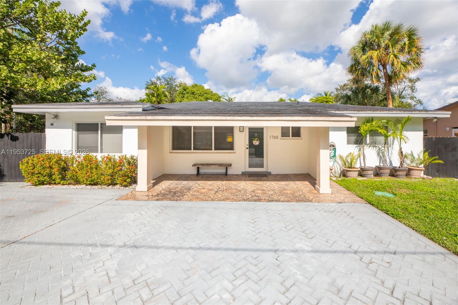 A single-story house features a covered front porch, a paved driveway, and a small lawn — 1765 NE 145th St, Miami FL 33181, MIAMI, FL