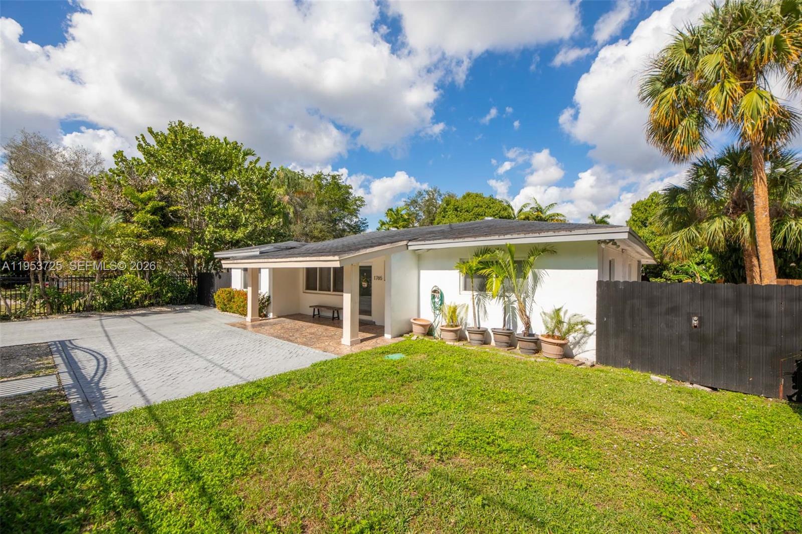 A single-story white house features a paved driveway, a covered porch, and a grassy yard — 1765 NE 145th St, Miami FL 33181, MIAMI, FL