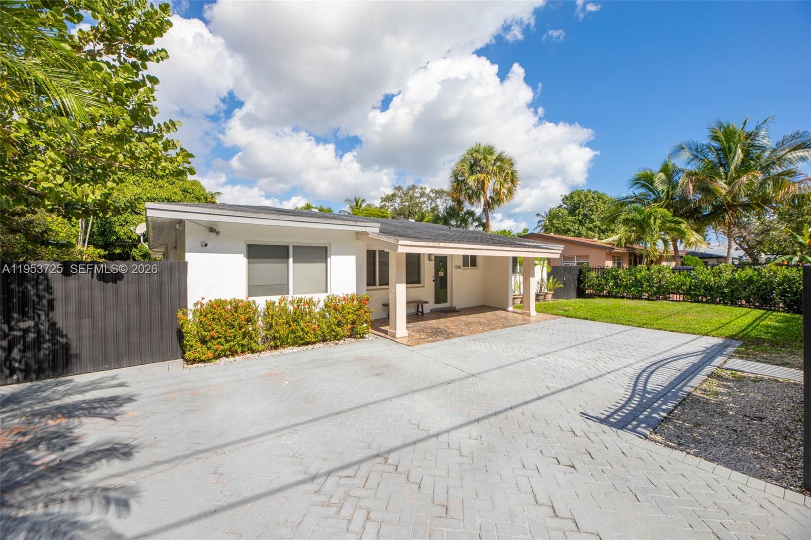 A single-story white house features a paved driveway, a covered porch, and surrounding palm trees — 1765 NE 145th St, Miami FL 33181, MIAMI, FL