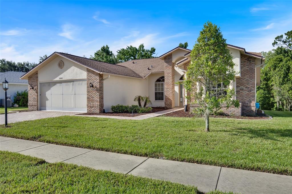 A single-story house with a brick and stucco exterior features a two-car garage — 18601 QUEEN BROOKS COURT, HUDSON, FL