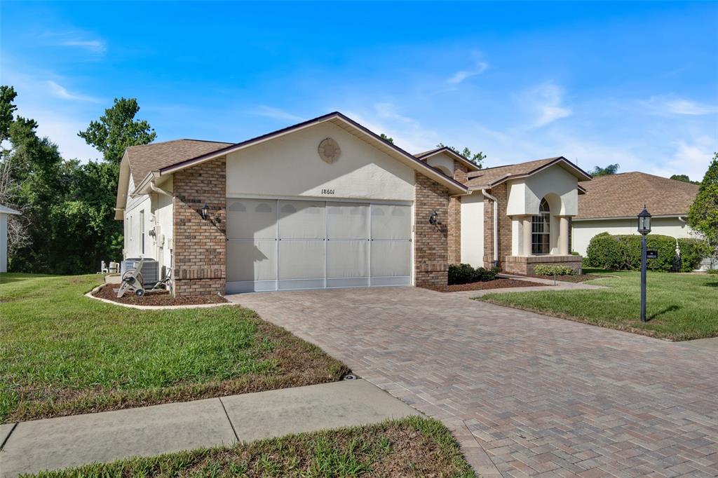 A single-story house with a brick and stucco exterior, a paved driveway, and a garage — 18601 QUEEN BROOKS COURT, HUDSON, FL