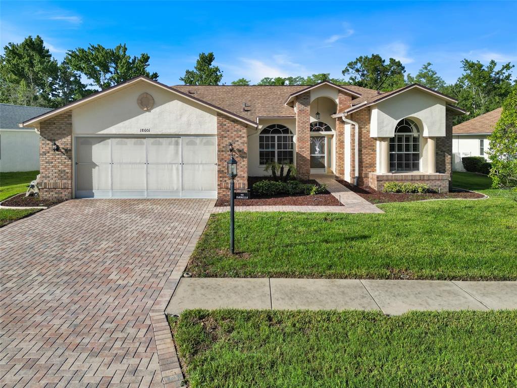 A single-story house with a brick and stucco exterior, a paved driveway, and a front lawn — 18601 QUEEN BROOKS COURT, HUDSON, FL