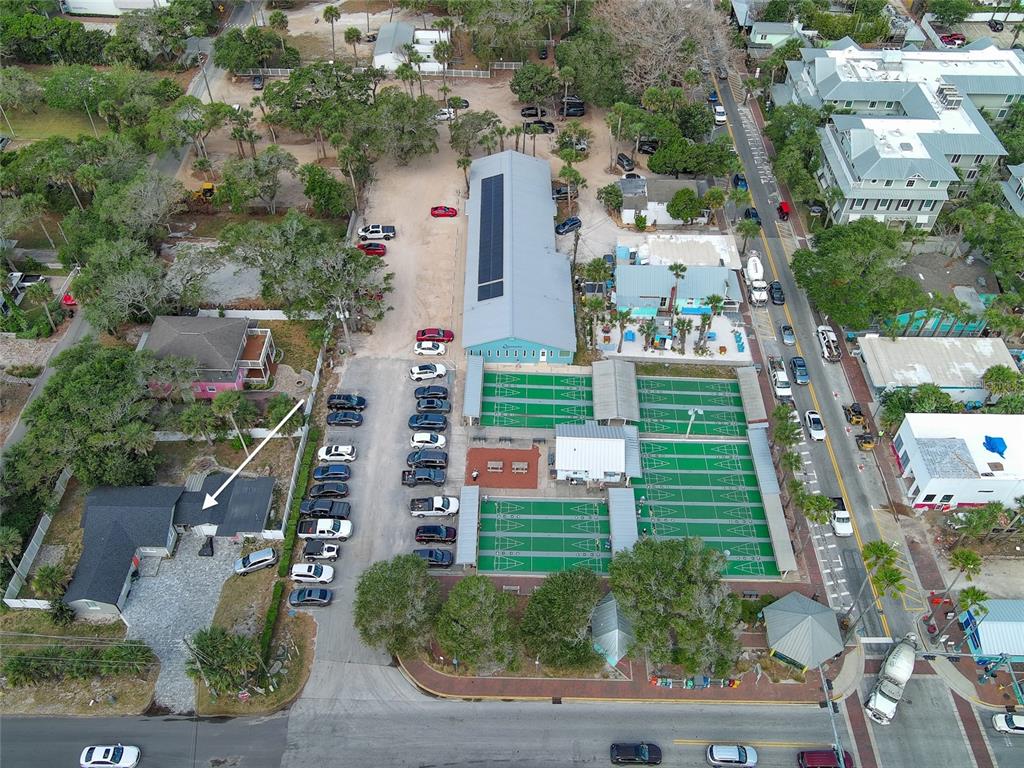 An aerial view shows a building with shuffleboard courts, a parking lot, and surrounding trees — 200 S PINE STREET, NEW SMYRNA BEACH, FL