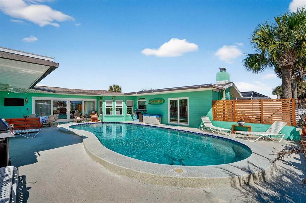 A turquoise house exterior features a curved swimming pool and a wooden privacy fence — 119 OLD CARRIAGE ROAD, PONCE INLET, FL
