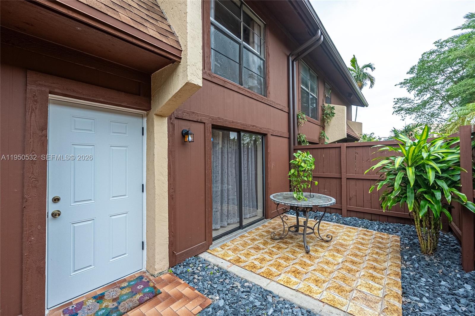 A patio area features a small table, a potted plant, and a white entry door — 6534 SW 114th Pl # 75, Miami FL 33173, MIAMI, FL