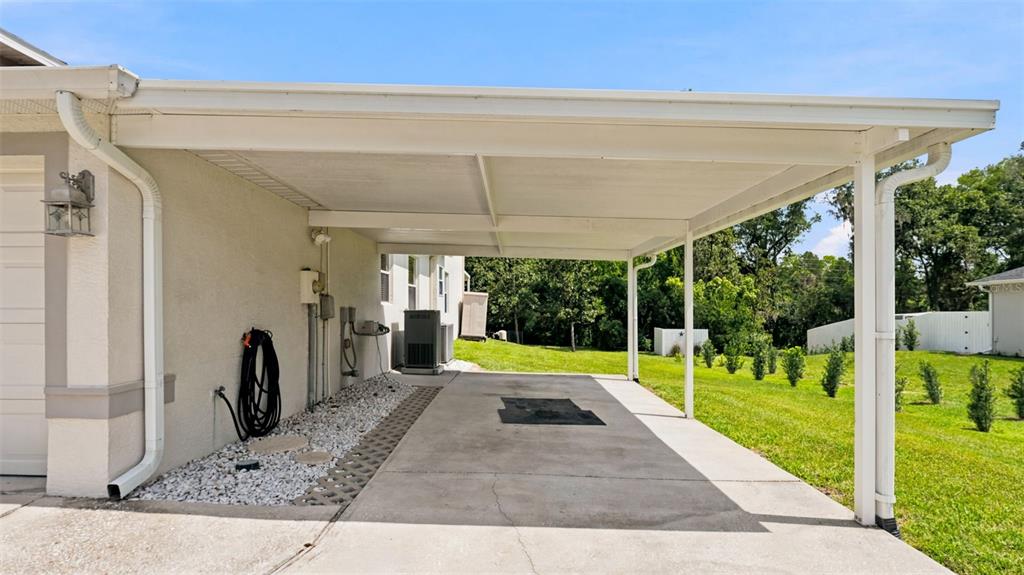 A concrete carport attached to the side of a house with a white metal roof — 13123 SADDLE WAY, BROOKSVILLE, FL
