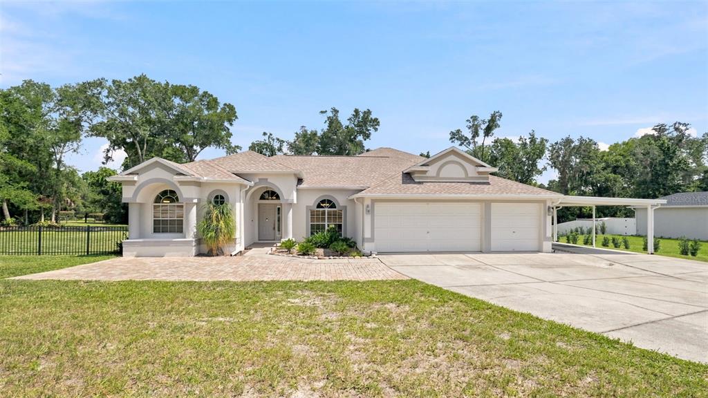 A single-story house with a white stucco exterior, arched windows, and a two-car garage — 13123 SADDLE WAY, BROOKSVILLE, FL