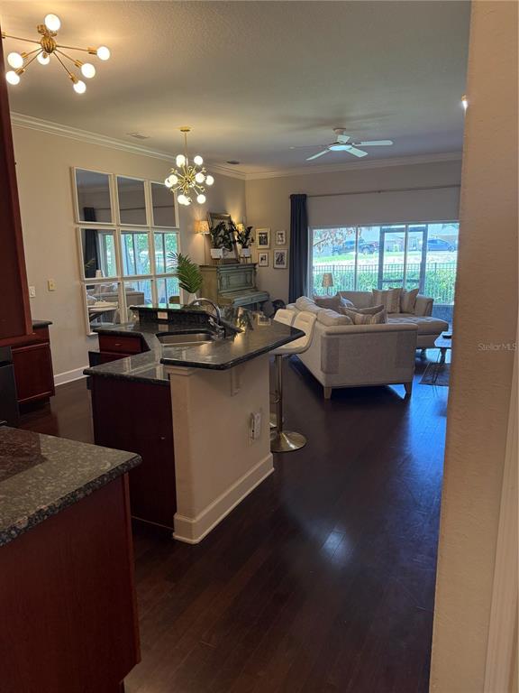 An open-concept kitchen with granite countertops overlooks a living room with a sliding glass door — 1018 GREEN GATE BOULEVARD, GROVELAND, FL