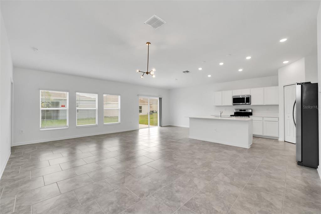 An open-concept kitchen and living area features white cabinetry, a kitchen island, and tile flooring — 243 HAYLEY STREET, WINTER HAVEN, FL
