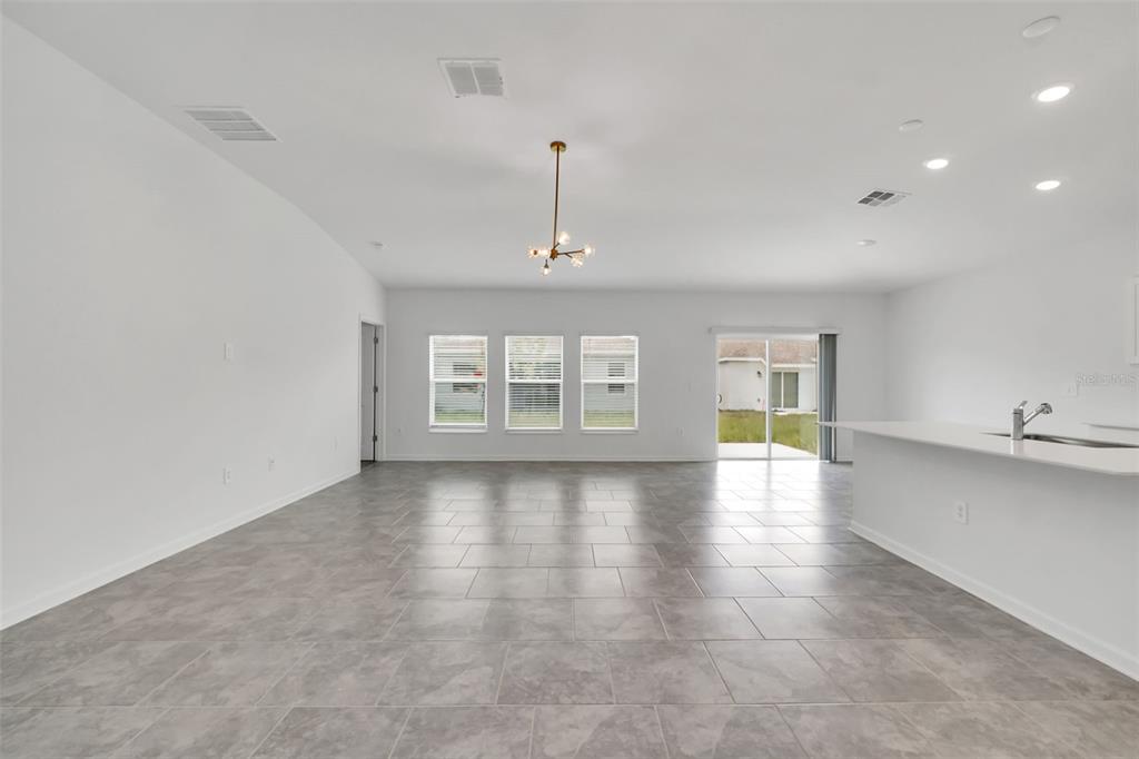 An open-concept living area features gray tile flooring, white walls, and a modern light fixture — 243 HAYLEY STREET, WINTER HAVEN, FL