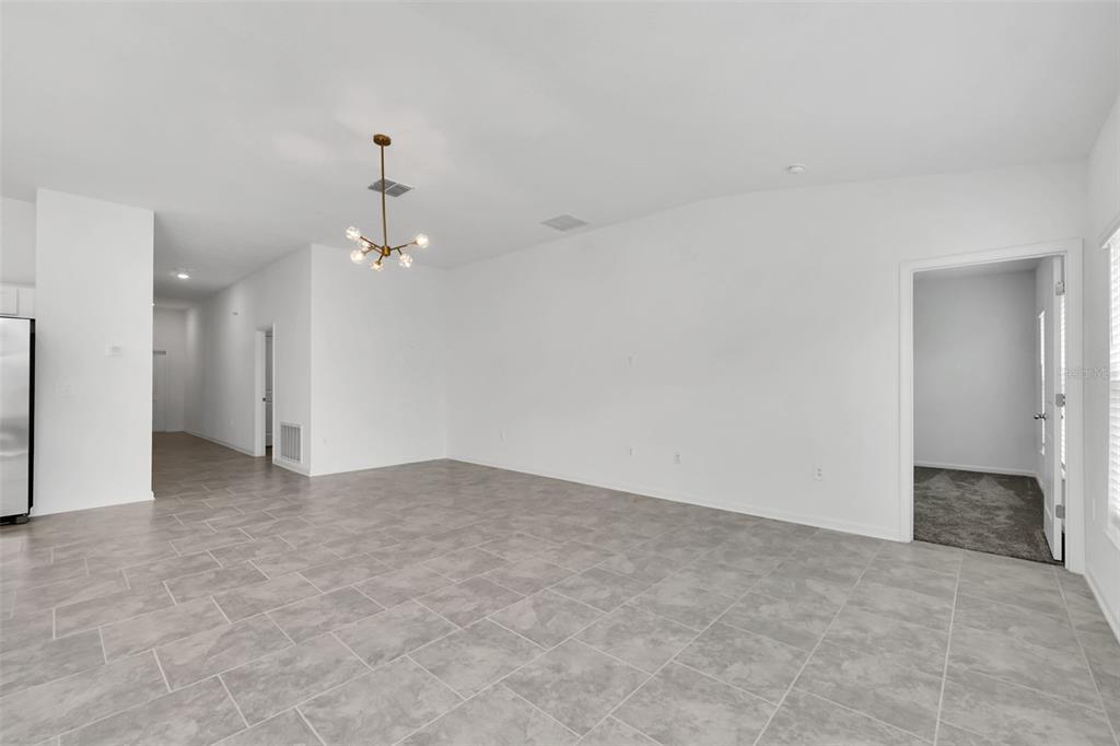 An empty room with white walls, gray tile flooring, and a modern chandelier — 243 HAYLEY STREET, WINTER HAVEN, FL