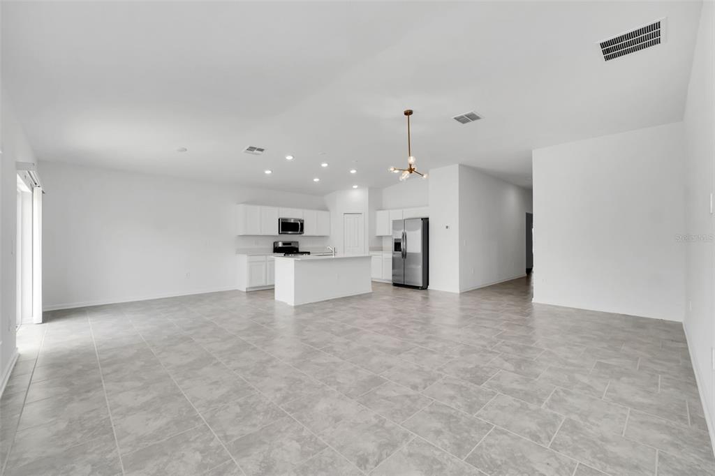 An open-concept kitchen with white cabinets, a center island, and light gray tile flooring — 243 HAYLEY STREET, WINTER HAVEN, FL