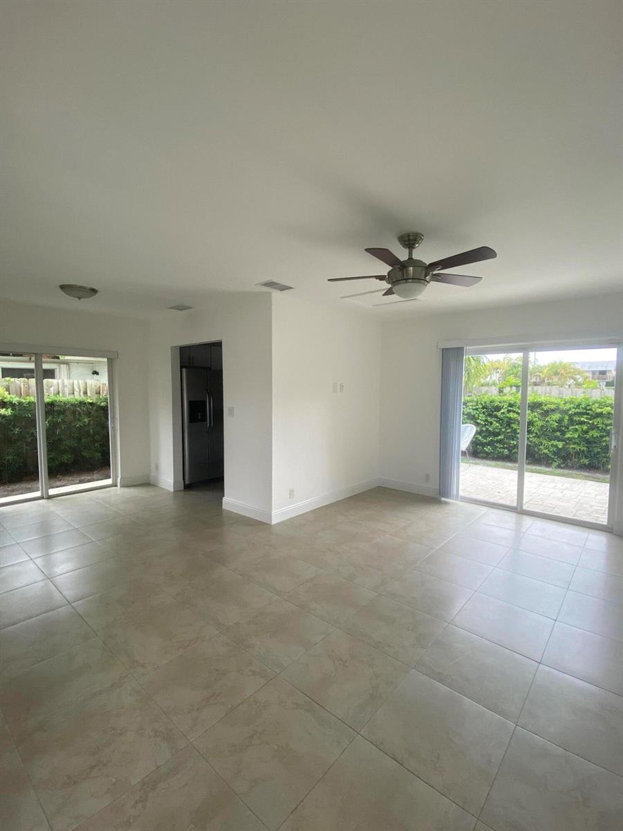 An open living area features light tile flooring, a ceiling fan, and two sliding glass doors — 560-570 NE 19th Avenue, Deerfield Beach FL 33441, DEERFIELD BEACH, FL