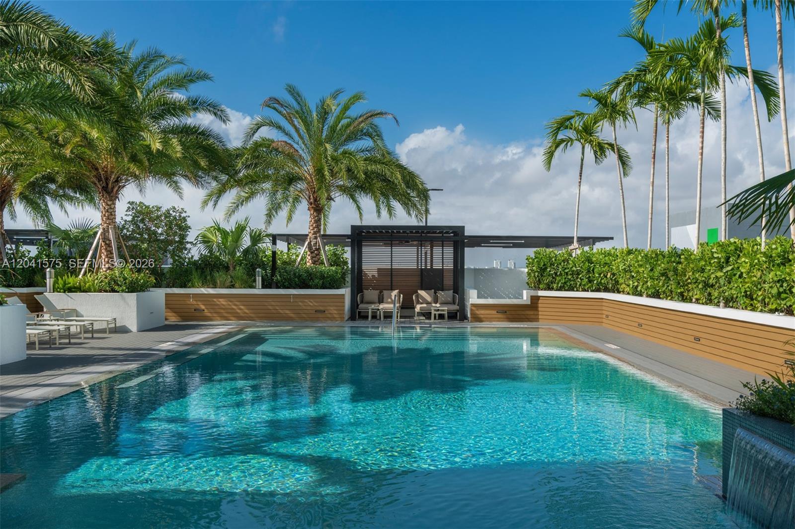 An outdoor swimming pool features a wooden deck, lounge chairs, and a shaded seating area — 221 SW 12th St # 511, Miami FL 33130, MIAMI, FL