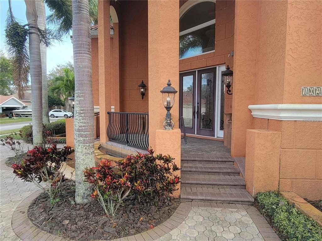 The exterior entrance features a paved walkway, steps, a metal railing, and decorative lanterns — 10209 THURSTON GROVES BOULEVARD, LARGO, FL