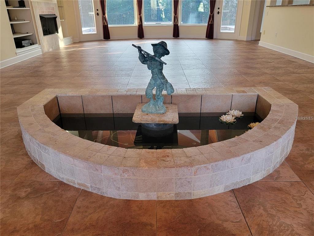 A semicircular indoor fountain with a bronze statue sits on a tiled floor in a room — 10209 THURSTON GROVES BOULEVARD, LARGO, FL