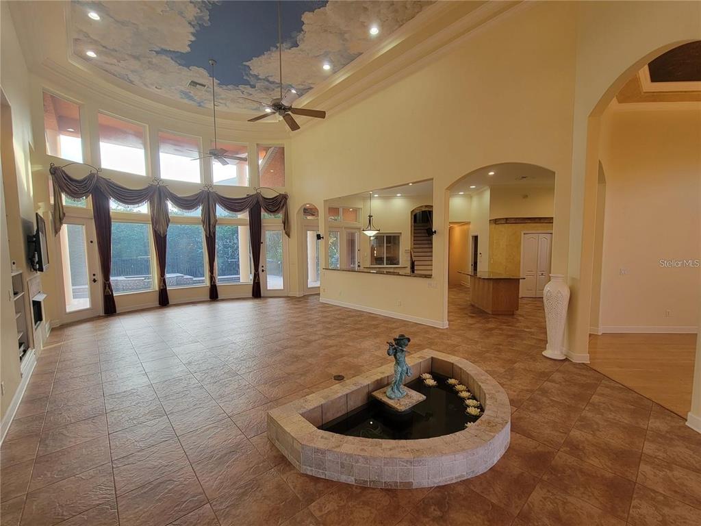 A spacious living room features a tiled floor, a central indoor fountain, and vaulted ceilings — 10209 THURSTON GROVES BOULEVARD, LARGO, FL