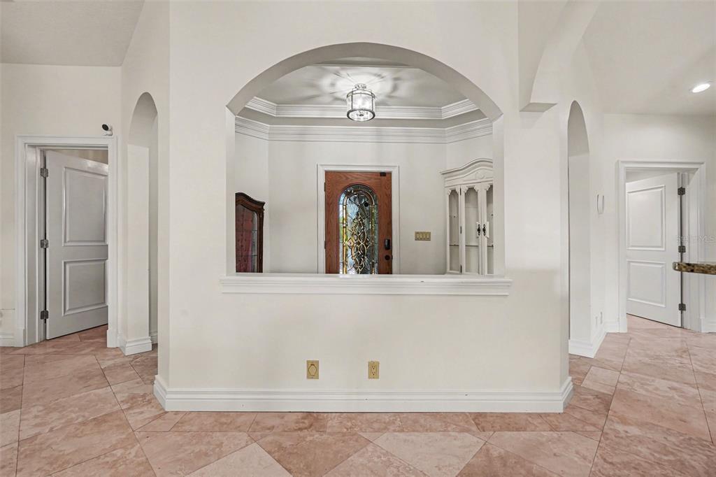 A view of an entryway with a wood front door, arched opening, and tile flooring — 840 3RD AVENUE S, TIERRA VERDE, FL