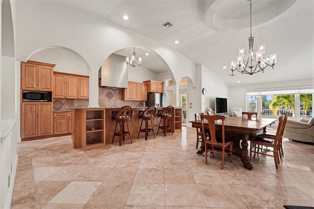 A kitchen with wood cabinets and a breakfast bar opens into a dining area — 840 3RD AVENUE S, TIERRA VERDE, FL
