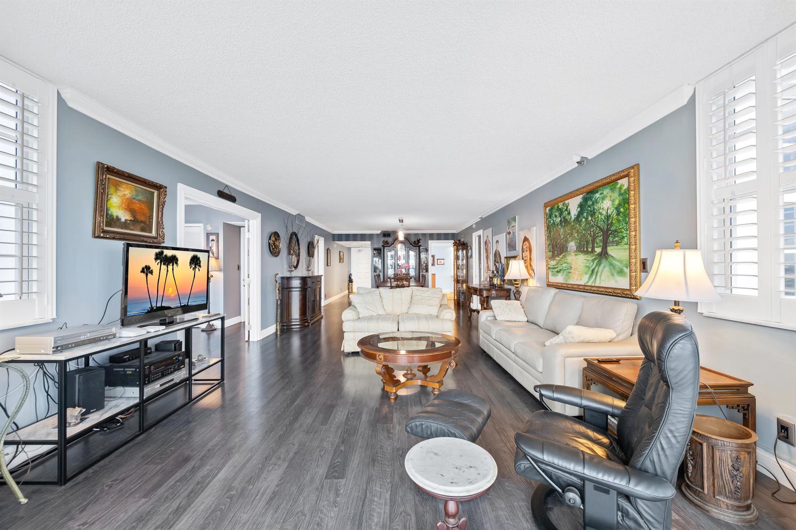 A living room features gray walls, dark wood-look flooring, a white sofa, and a black recliner — 2900 N Course Drive # 909, Pompano Beach FL 33069, POMPANO BEACH, FL