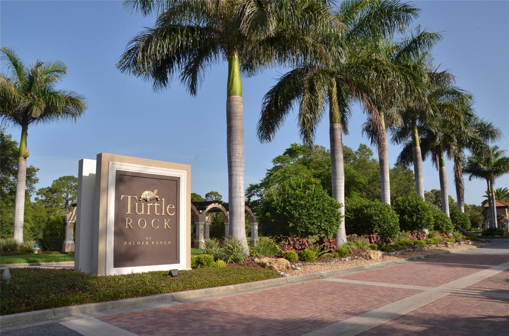 A stone monument sign for Turtle Rock on Palmer Ranch stands beside a brick road — 5121 GLADE FERN COURT, SARASOTA, FL