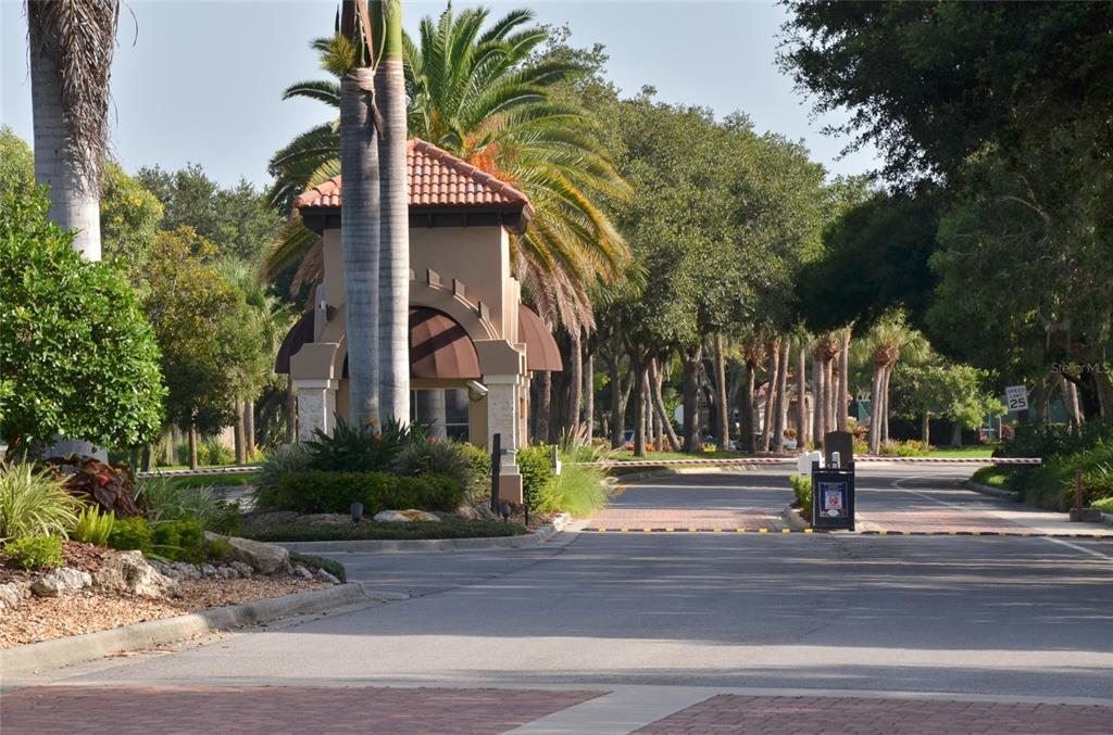 A gated entrance features a guardhouse with a tile roof and palm trees — 5121 GLADE FERN COURT, SARASOTA, FL