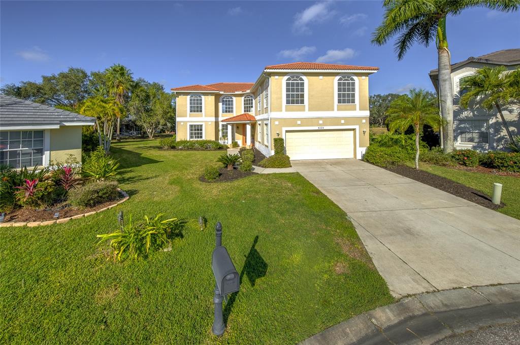 A two-story house with a tan stucco exterior, tile roof, and a concrete driveway — 5121 GLADE FERN COURT, SARASOTA, FL