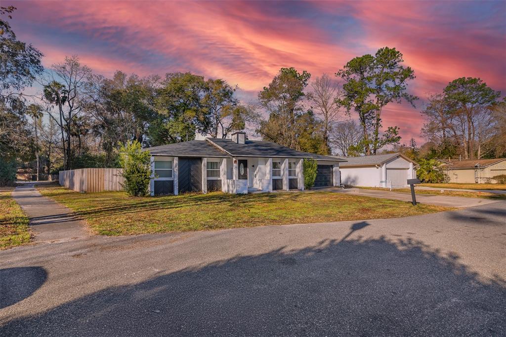 A single-story house with a white exterior and dark accents sits on a grassy lot — 872 FALKIRK DRIVE, WINTER SPRINGS, FL