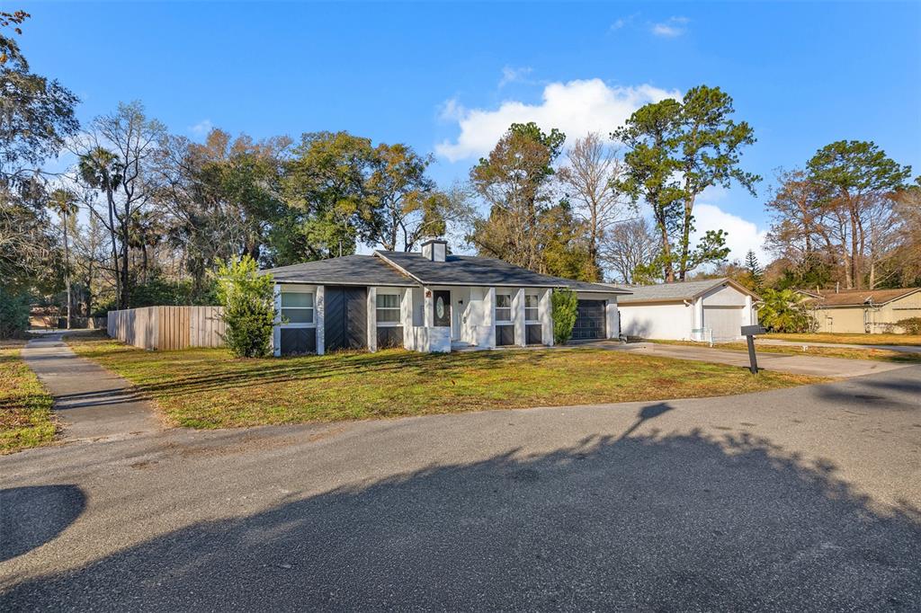 A single-story house with a white brick exterior and a dark roof sits on a lawn — 872 FALKIRK DRIVE, WINTER SPRINGS, FL