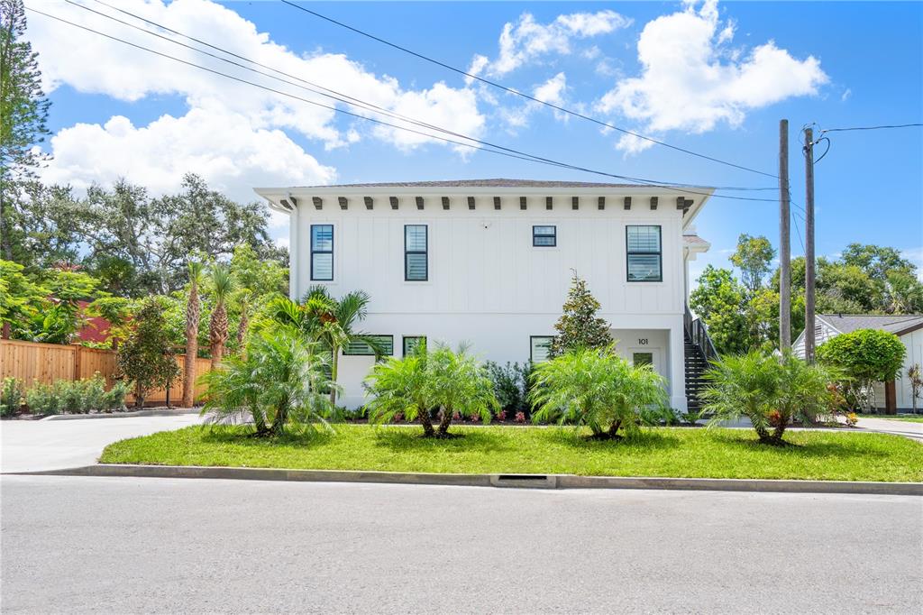 A two-story white building with black-framed windows sits behind a landscaped lawn — 1234 15TH STREET UNIT 201, SARASOTA, FL