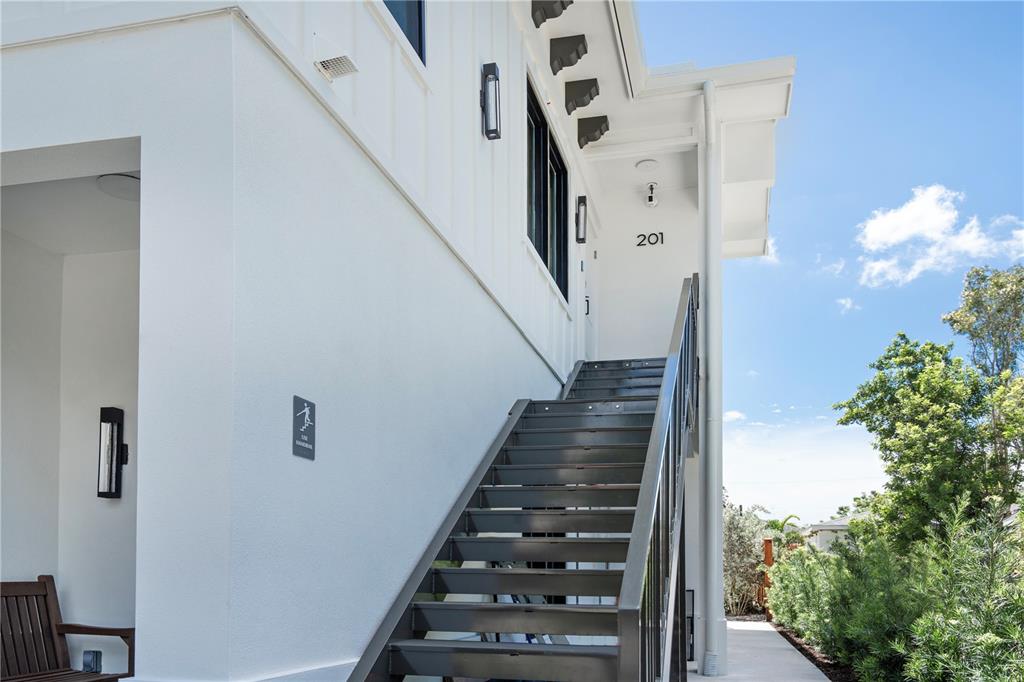 An exterior view shows a white building with metal stairs leading to a numbered entrance — 1234 15TH STREET UNIT 201, SARASOTA, FL