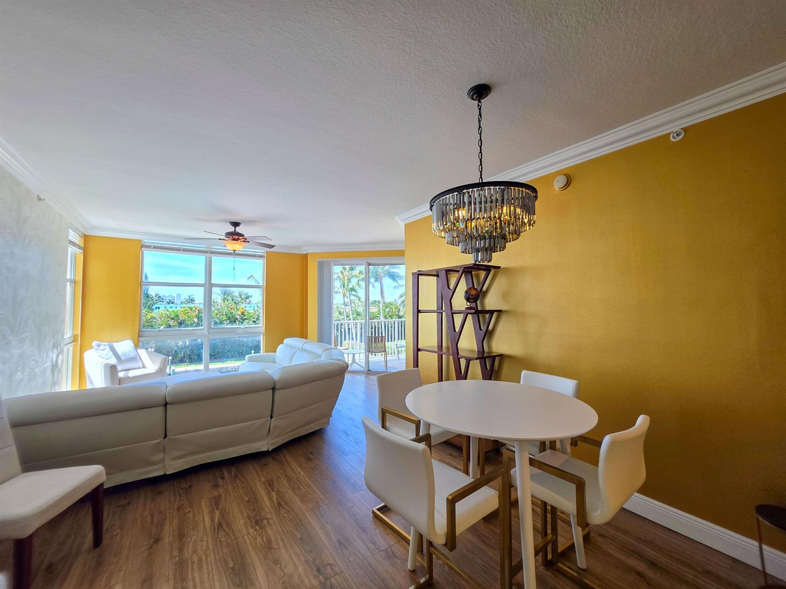 A dining area with a round table and chandelier sits beside a living room with yellow walls — 806 E Windward Way # 323, Lantana FL 33462, LANTANA, FL