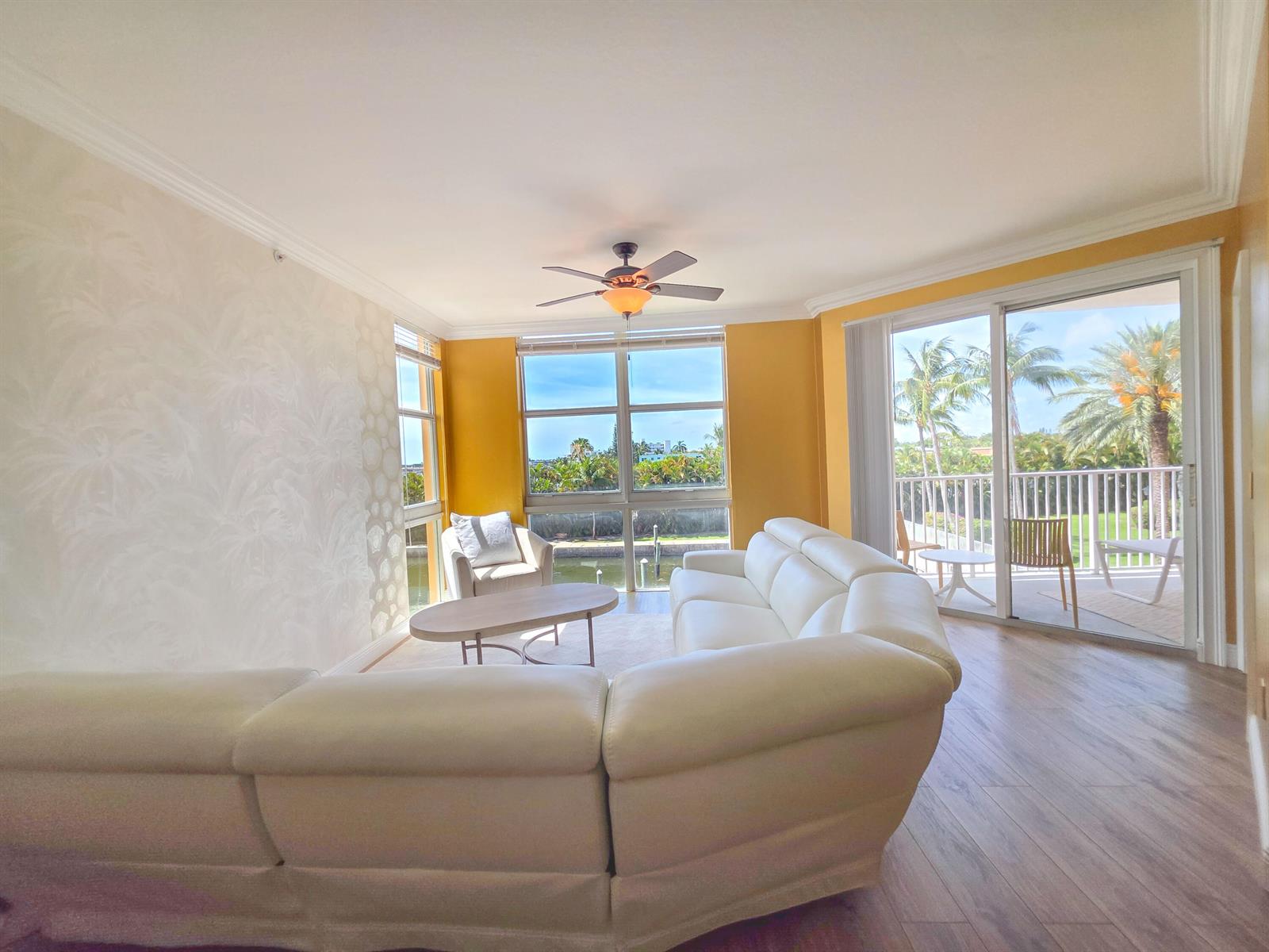 A living room with a white sectional sofa, yellow walls, and a balcony overlooking water — 806 E Windward Way # 323, Lantana FL 33462, LANTANA, FL