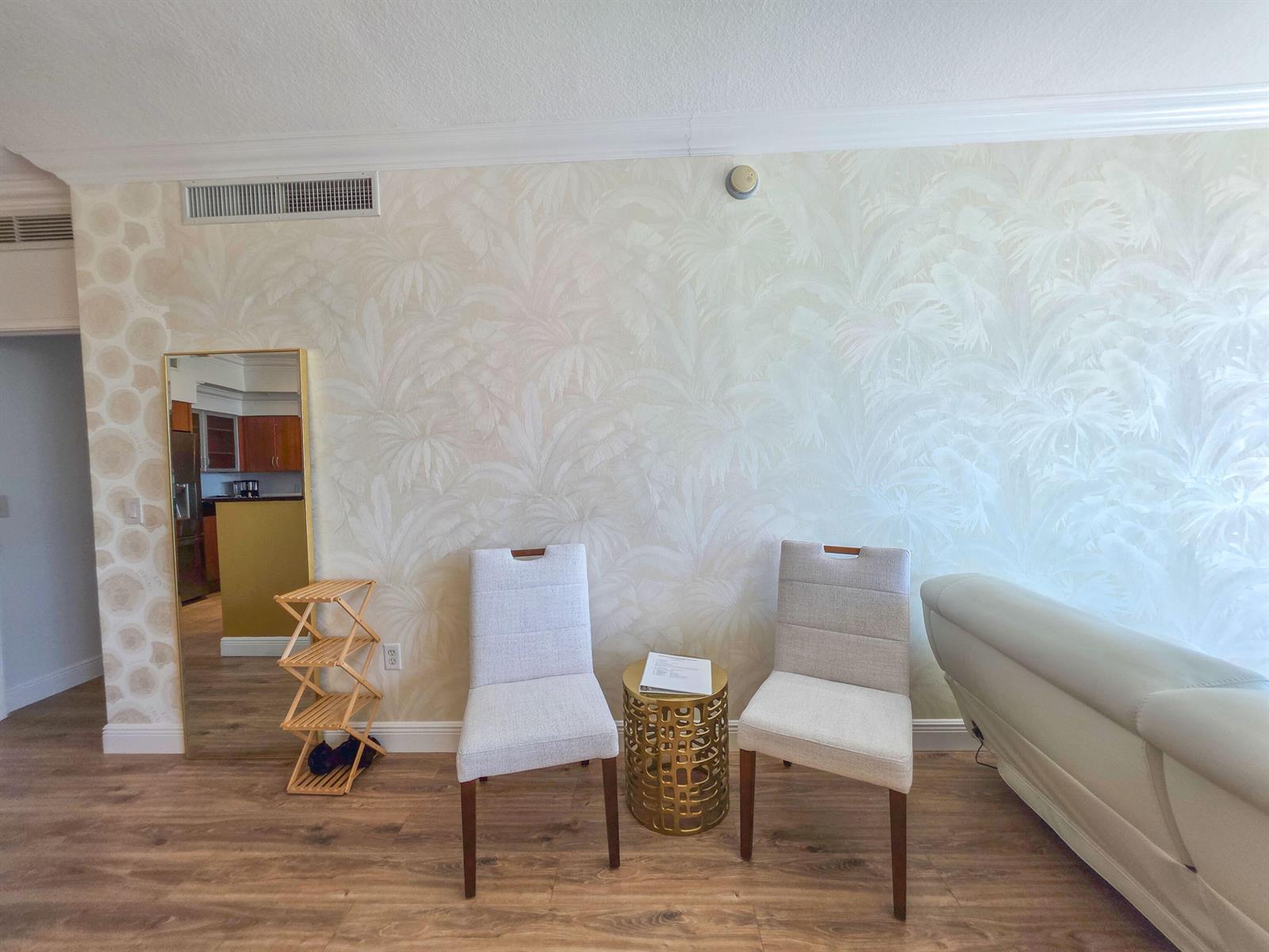 A room features light-colored palm-patterned wallpaper, two upholstered chairs, a gold side table, and flooring — 806 E Windward Way # 323, Lantana FL 33462, LANTANA, FL