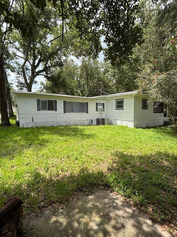 A white mobile home sits on a grassy lot surrounded by mature trees — 24739 AUDREY ROAD, LAND O LAKES, FL