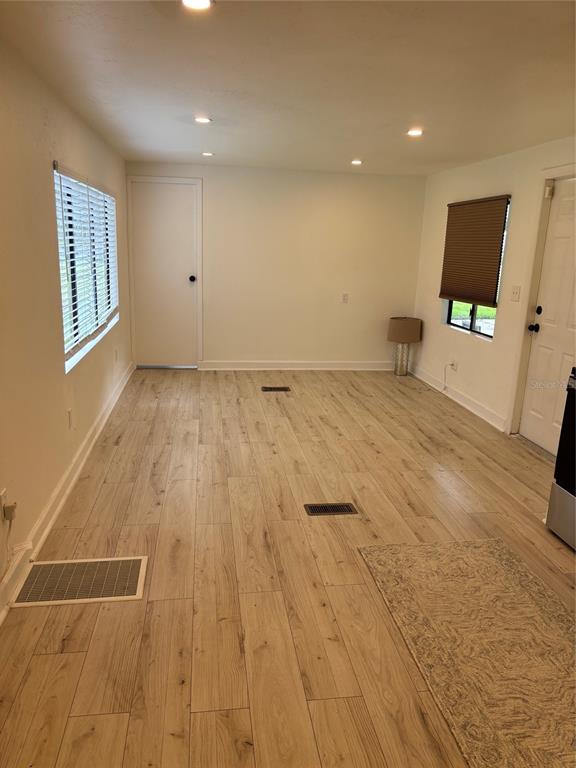 A room with light wood-look flooring, recessed lighting, a window with blinds, and two doors — 24739 AUDREY ROAD, LAND O LAKES, FL